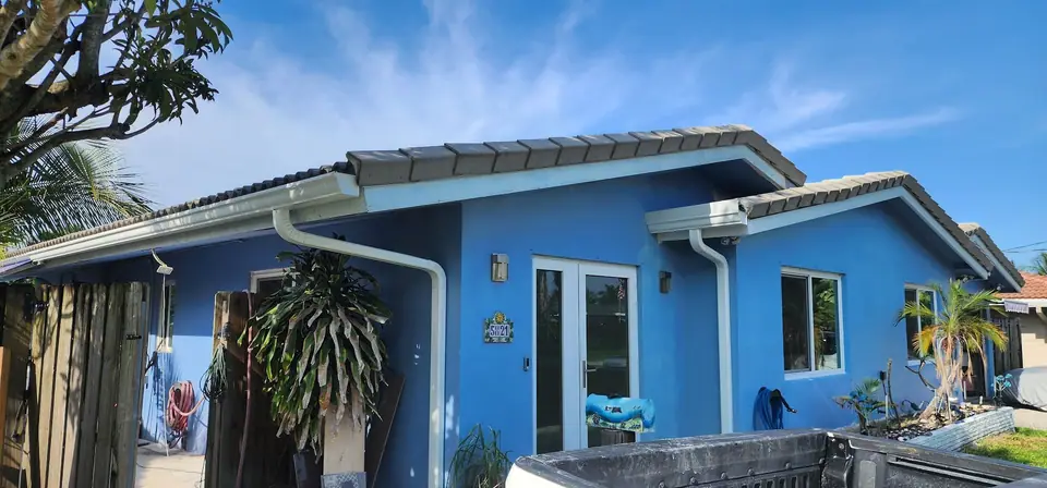 White gutters and downspouts on a bright blue stucco home