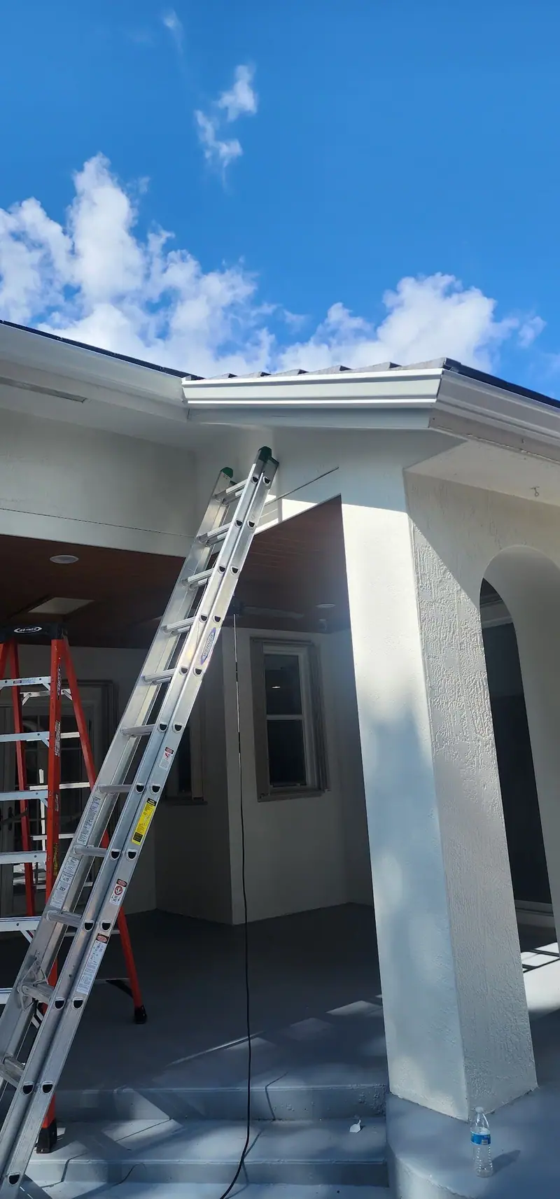 Ladders up at a white home during a gutter install