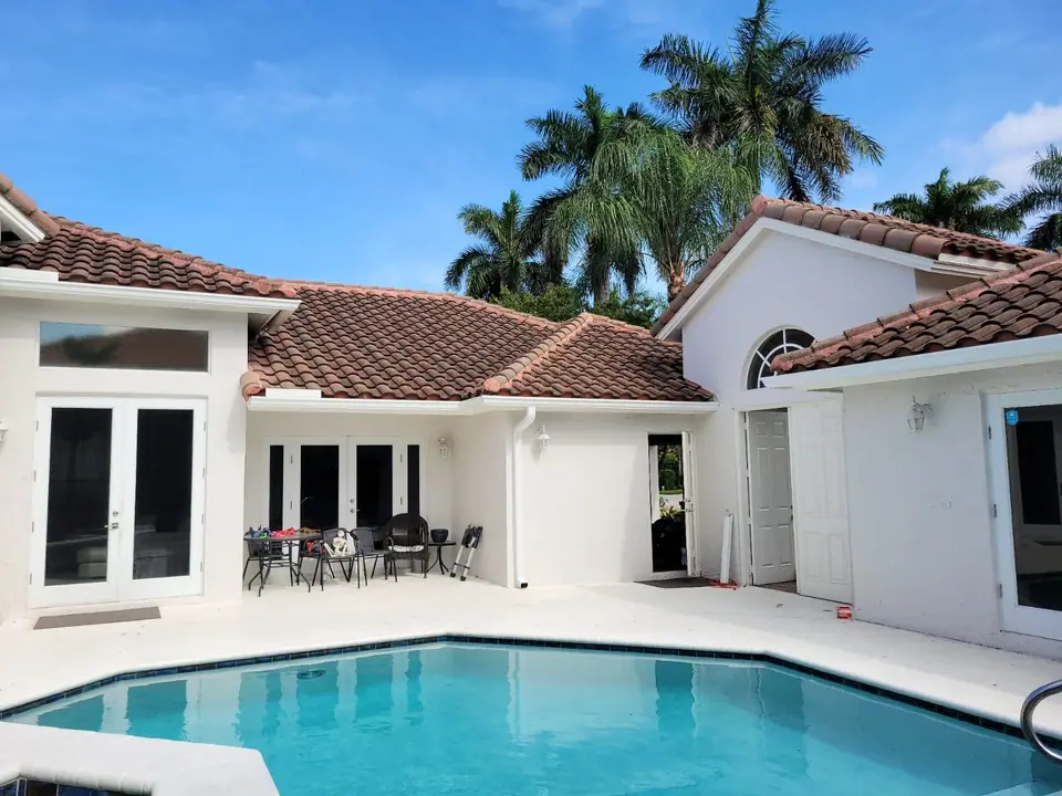 White seamless gutters along the red tile roof of a South Florida pool home